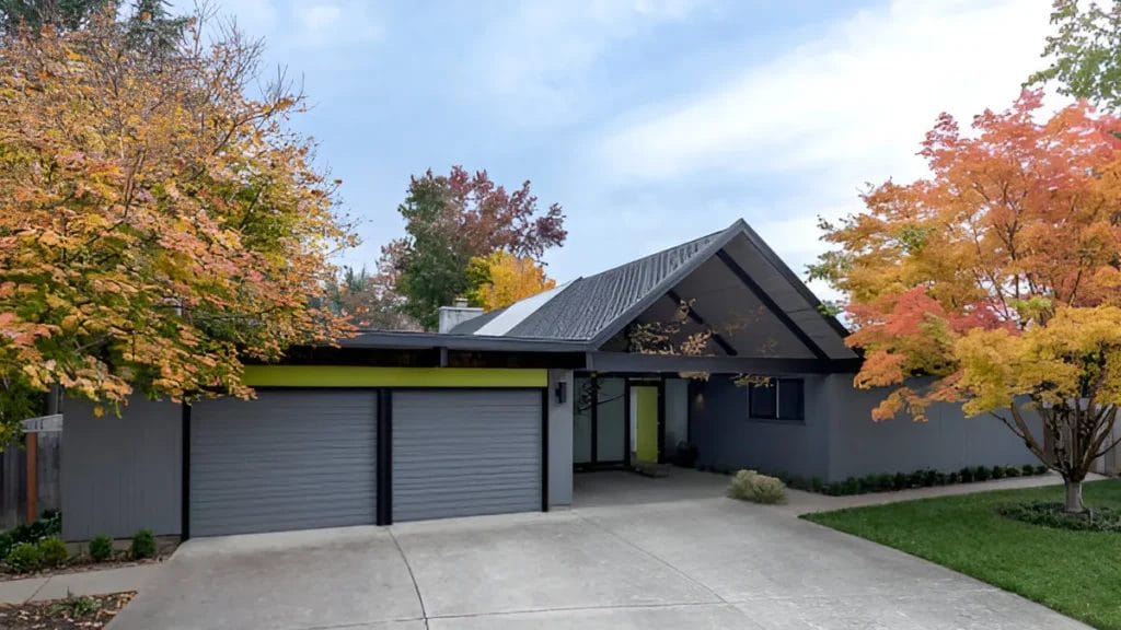 A photo of a mid-century modern home with a flat roof, large windows, and an open floor plan