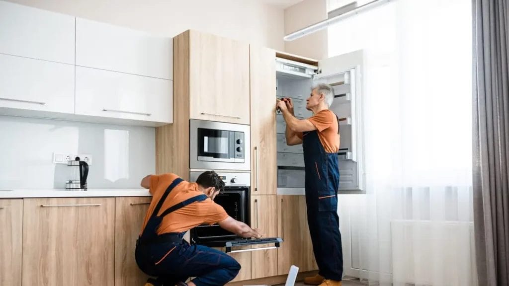 workers installing oven adjusting cabinets modern kitchen